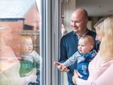 Photo of family in house smiling and looking out of glass door