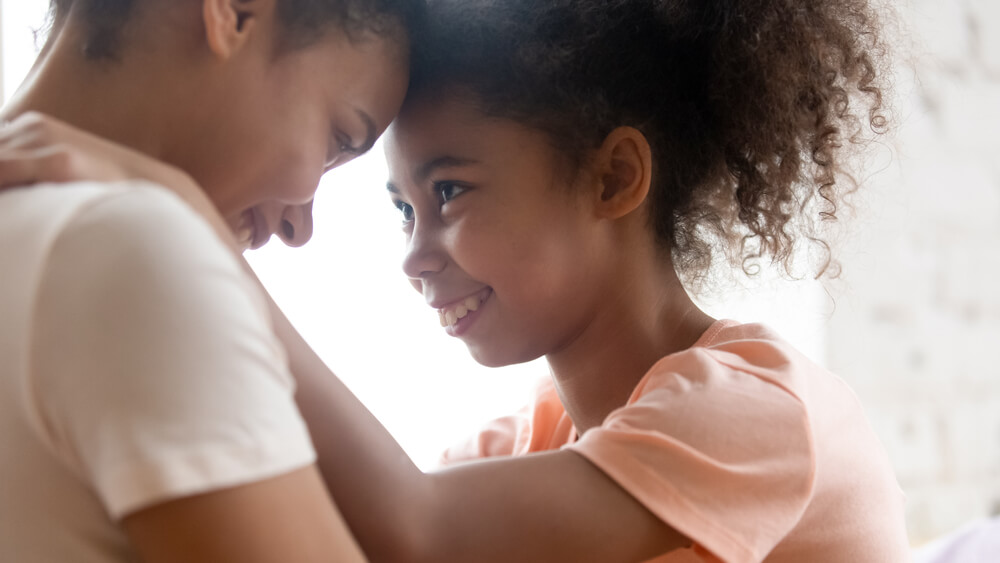 A mother and her daughter embracing, touching foreheads.