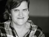 Black and white photo of woman in checked shirt smiling at camera