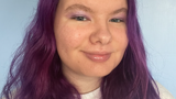 Photo of person with purple hair smiling at camera