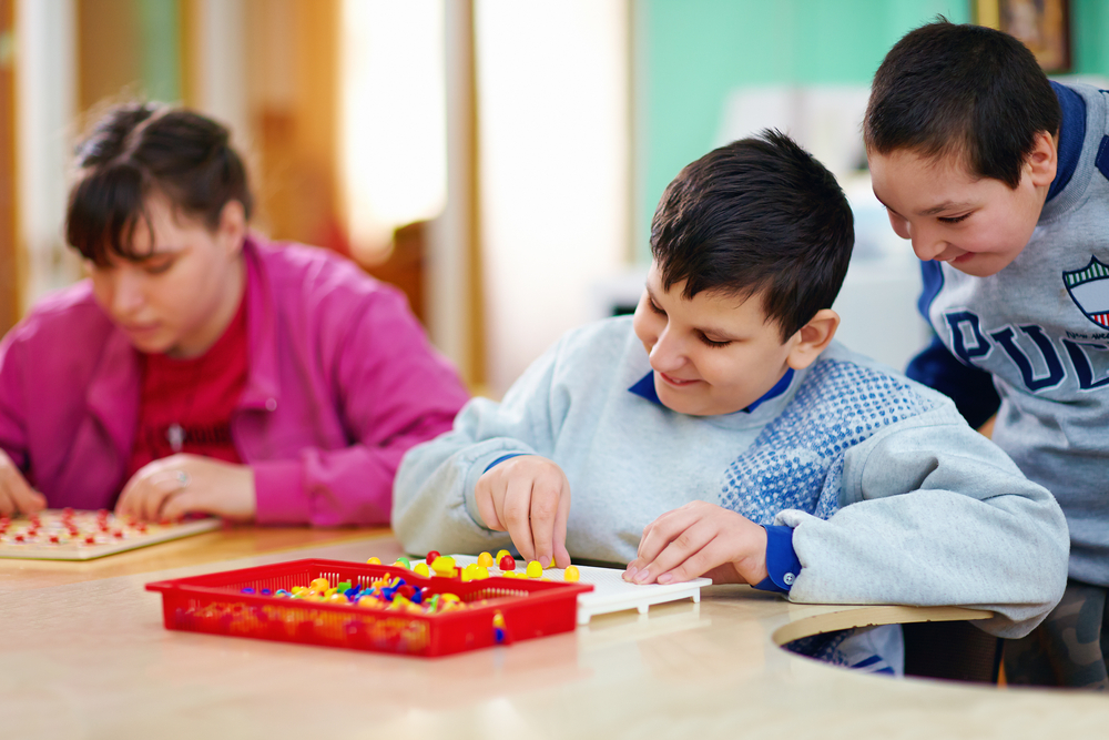 Photo of three children playing together at a table.