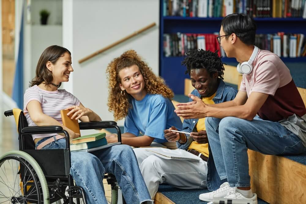 Photo of 4 young people in a college sitting and talking. 